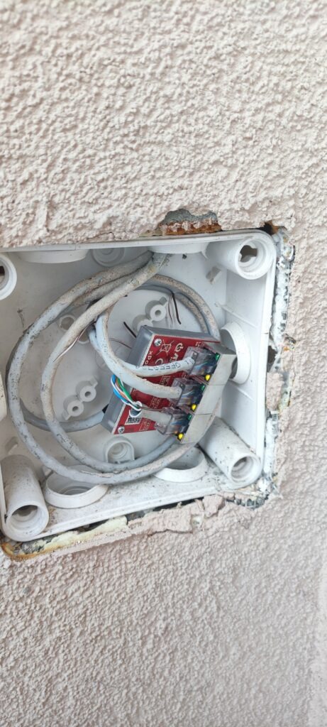 otwarta puszka elektryczna z przewodami w ścianie – przykład instalacji wymagającej oceny przed modernizacją
